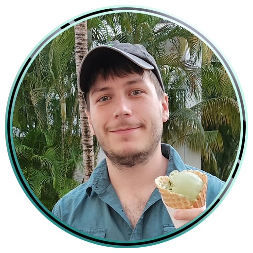 A photo of Drew holding an ice cream cone. There are palm trees in the background.